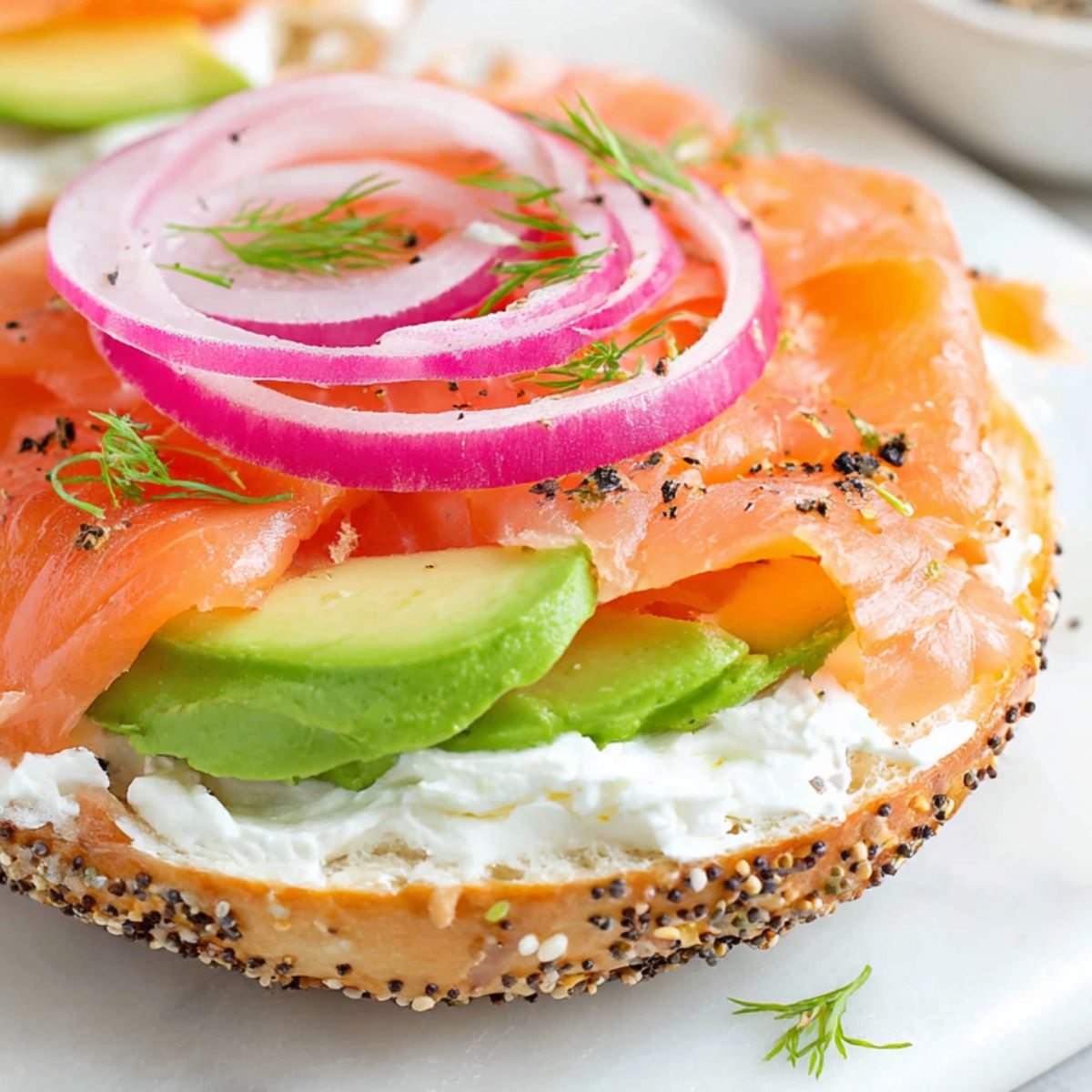 Homemade salmon cream cheese bagel on a white kitchen counter, photographed from above.