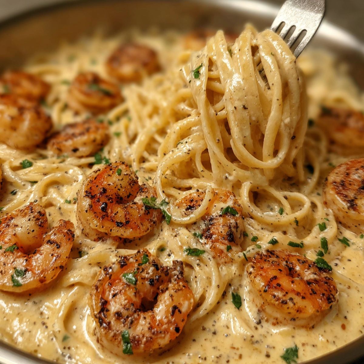 Mixing pasta and shrimp into the creamy Cajun sauce in a pan