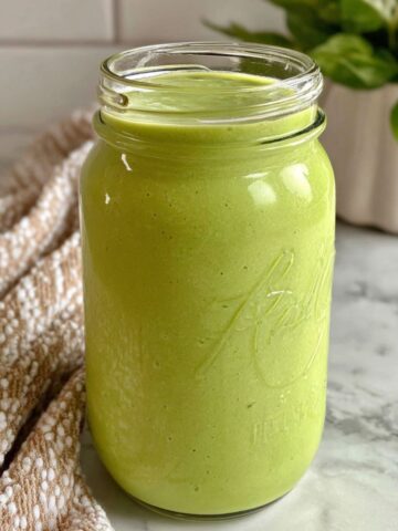 Homemade flat belly smoothie in a mason jar on a white kitchen counter.