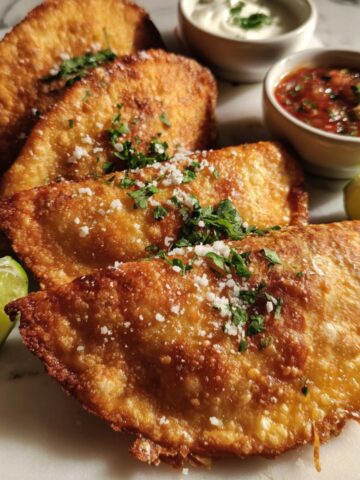 Homemade quesadillas fritas mexicanas on a kitchen counter with salsa and lime, captured from above in a casual setting
