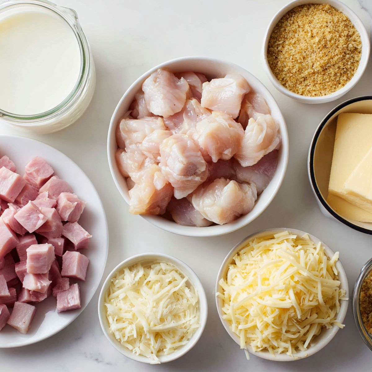 Ingredients for chicken cordon bleu casserole spread casually on a white kitchen counter