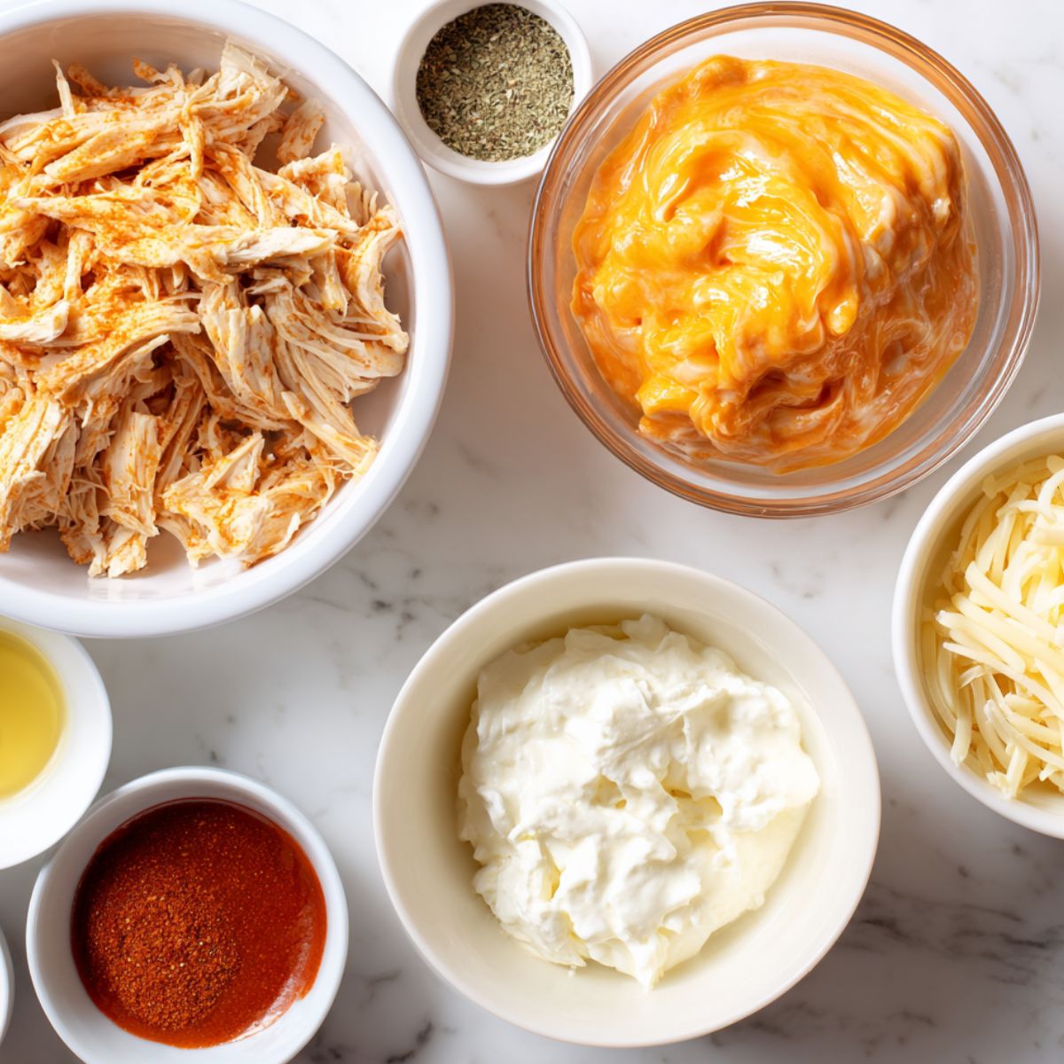 Flat lay of ingredients for keto buffalo chicken dip on a white kitchen counter
