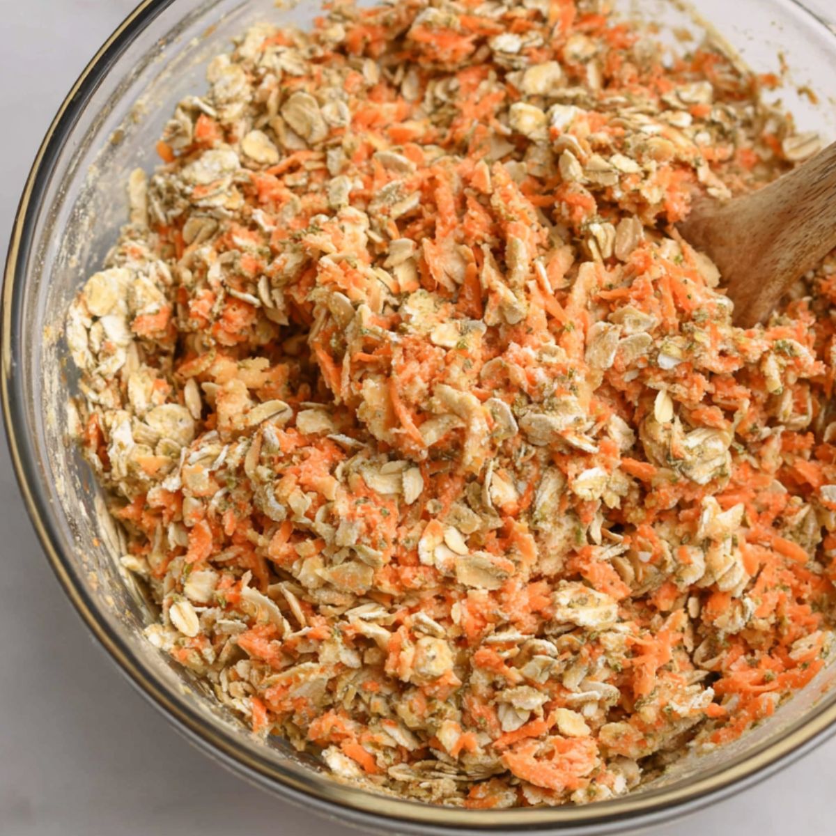 Dry ingredients and grated carrots being mixed in a bowl