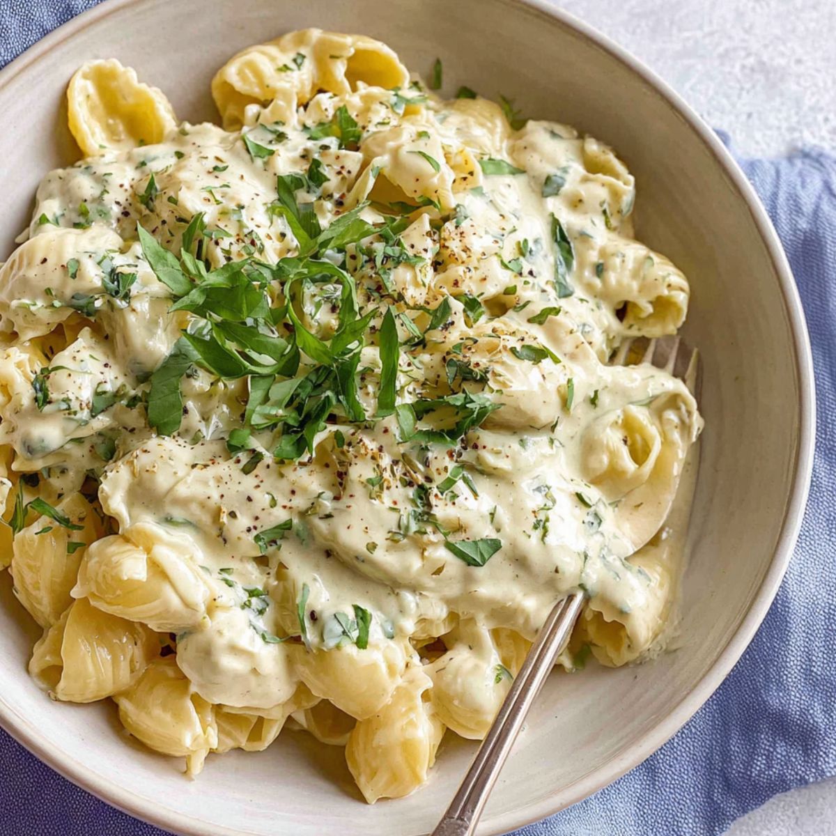 Serving healthy alfredo sauce over pasta with herbs.
