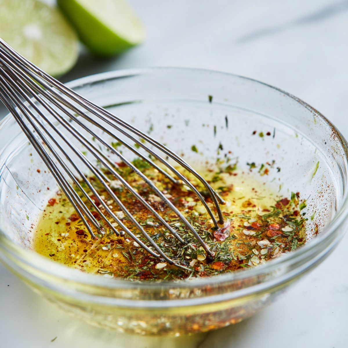 Tangy vinaigrette being whisked in a glass bowl.