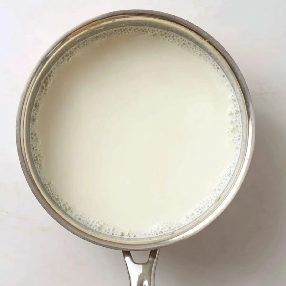Heating milk and cream in a saucepan to make custard base for ice cream.