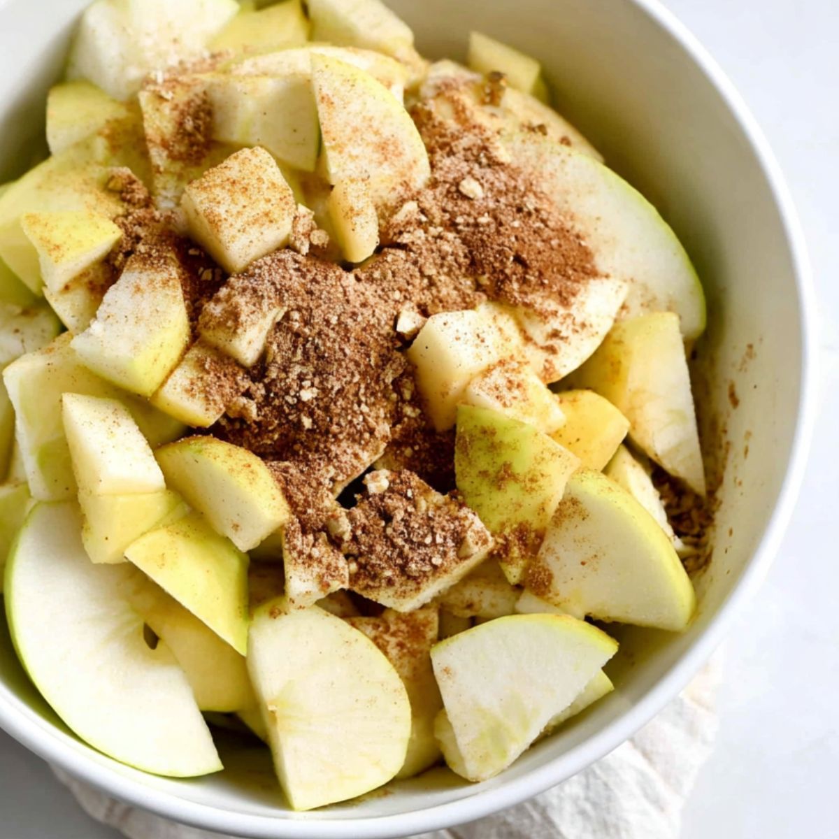 Apple slices mixed with cinnamon and sugar in a bowl