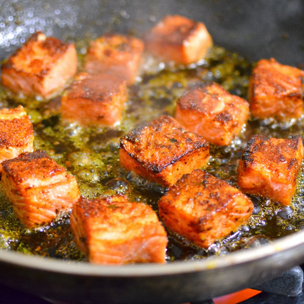 Salmon cubes cooking in a pan with soy sauce and seasoning