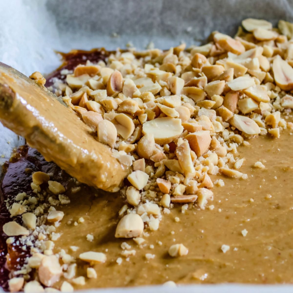 Peanut butter and chopped peanuts spread over the date layer