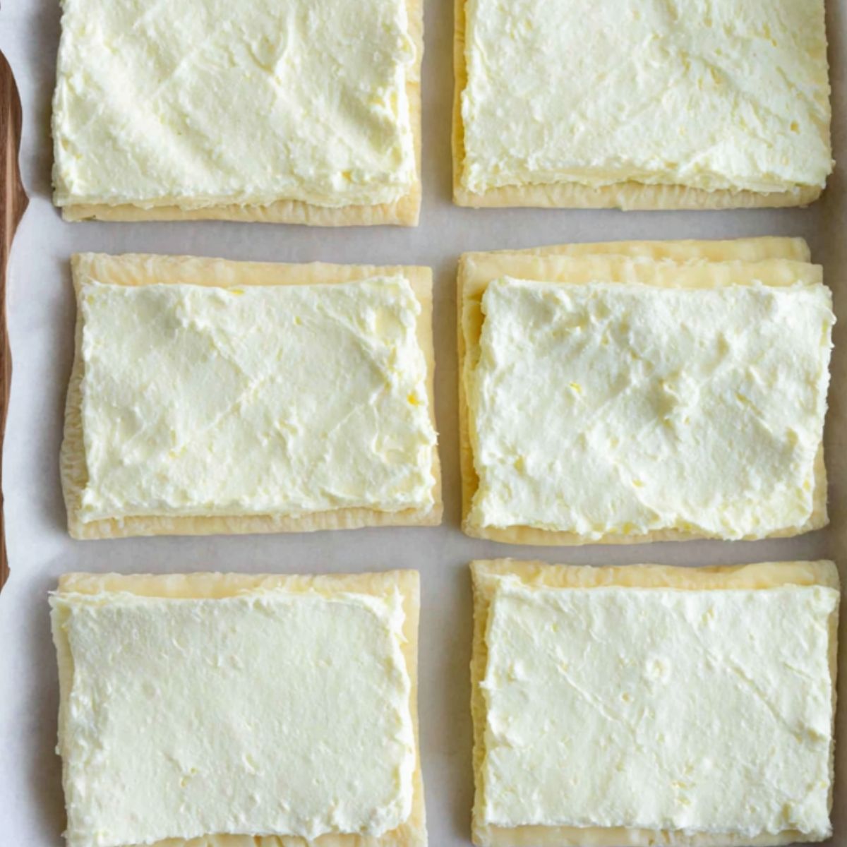 Cream cheese filling being spread onto puff pastry