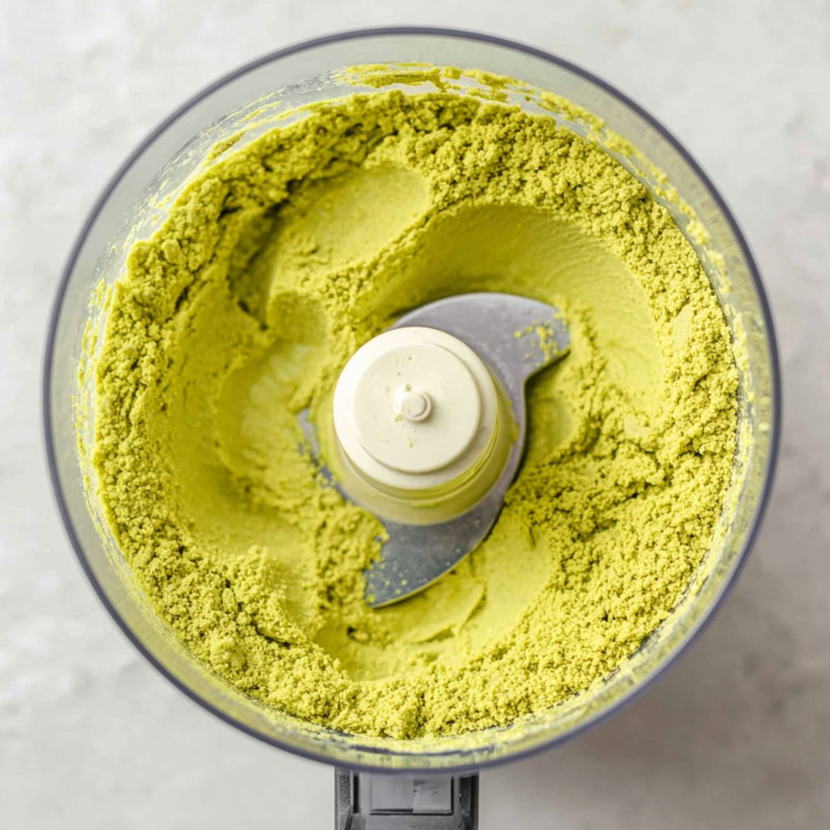 Ground pistachios forming coarse paste in food processor