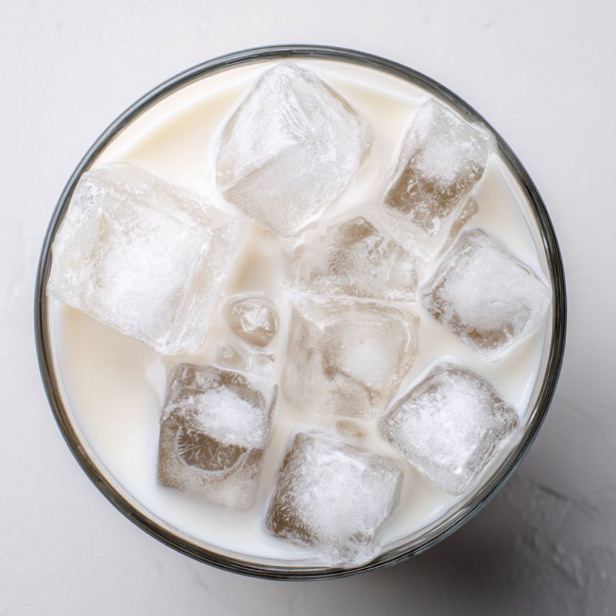 Milk being poured into a glass of iced coffee