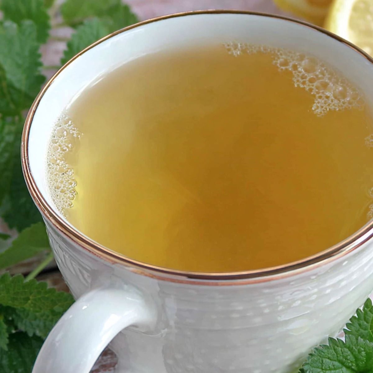 Pouring lemon balm tea through a strainer into a mug.