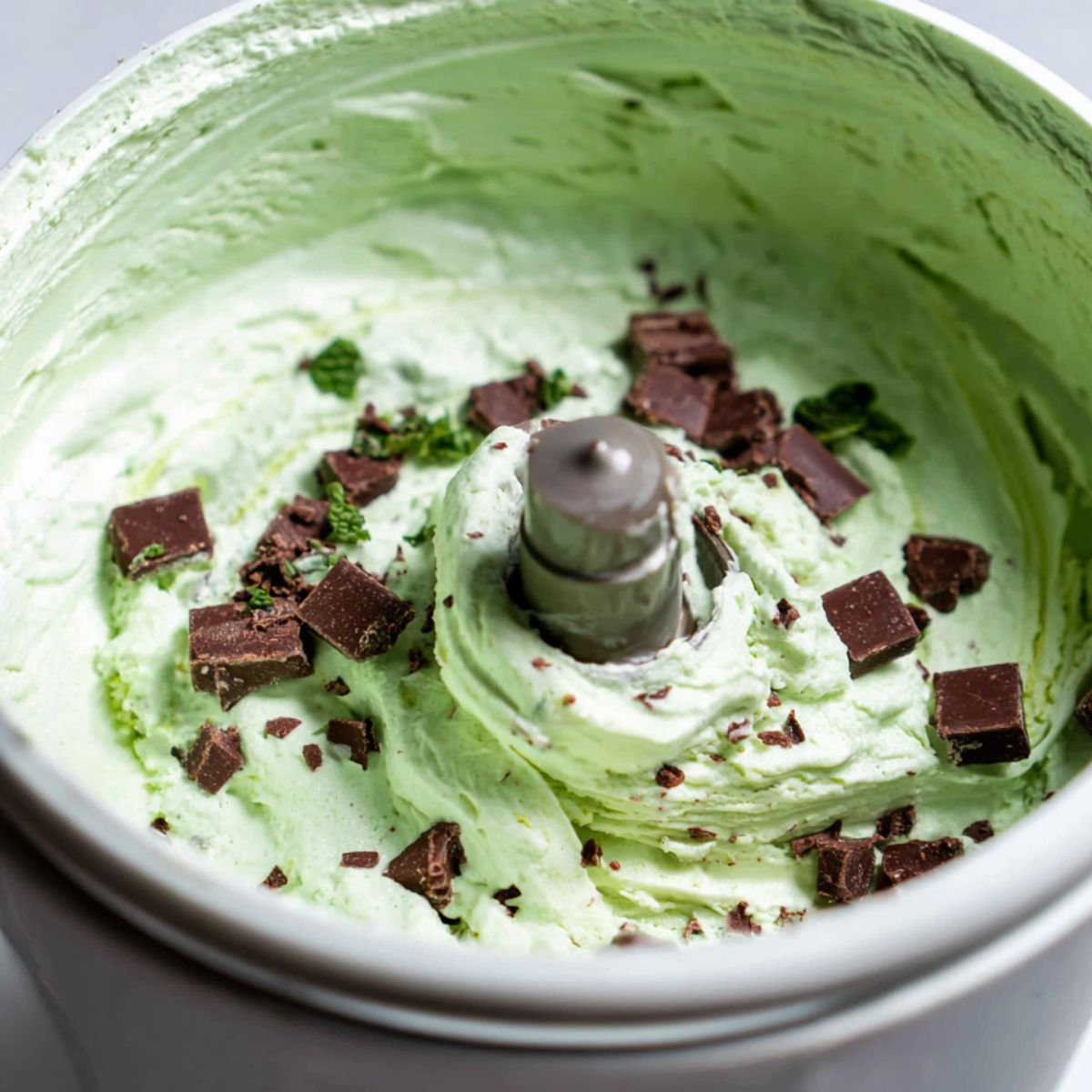 Chocolate chips being added to churning homemade mint ice cream.