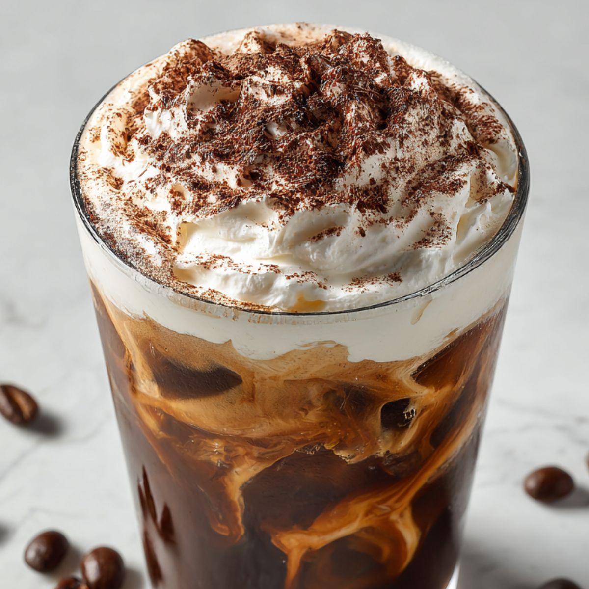 Dusting cocoa powder over finished tiramisu iced coffee with toppings