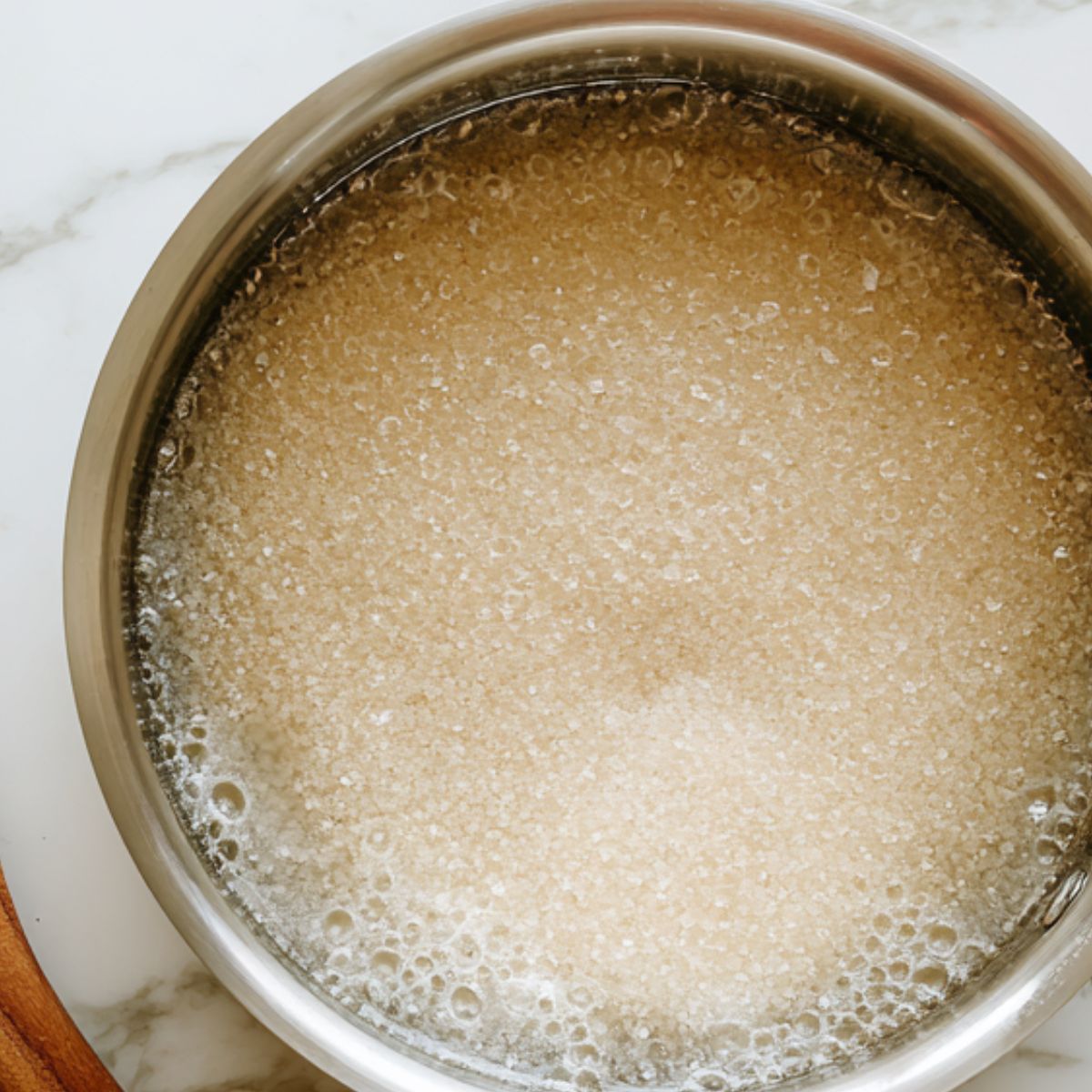 Sugar and water being combined in a saucepan for vanilla syrup.