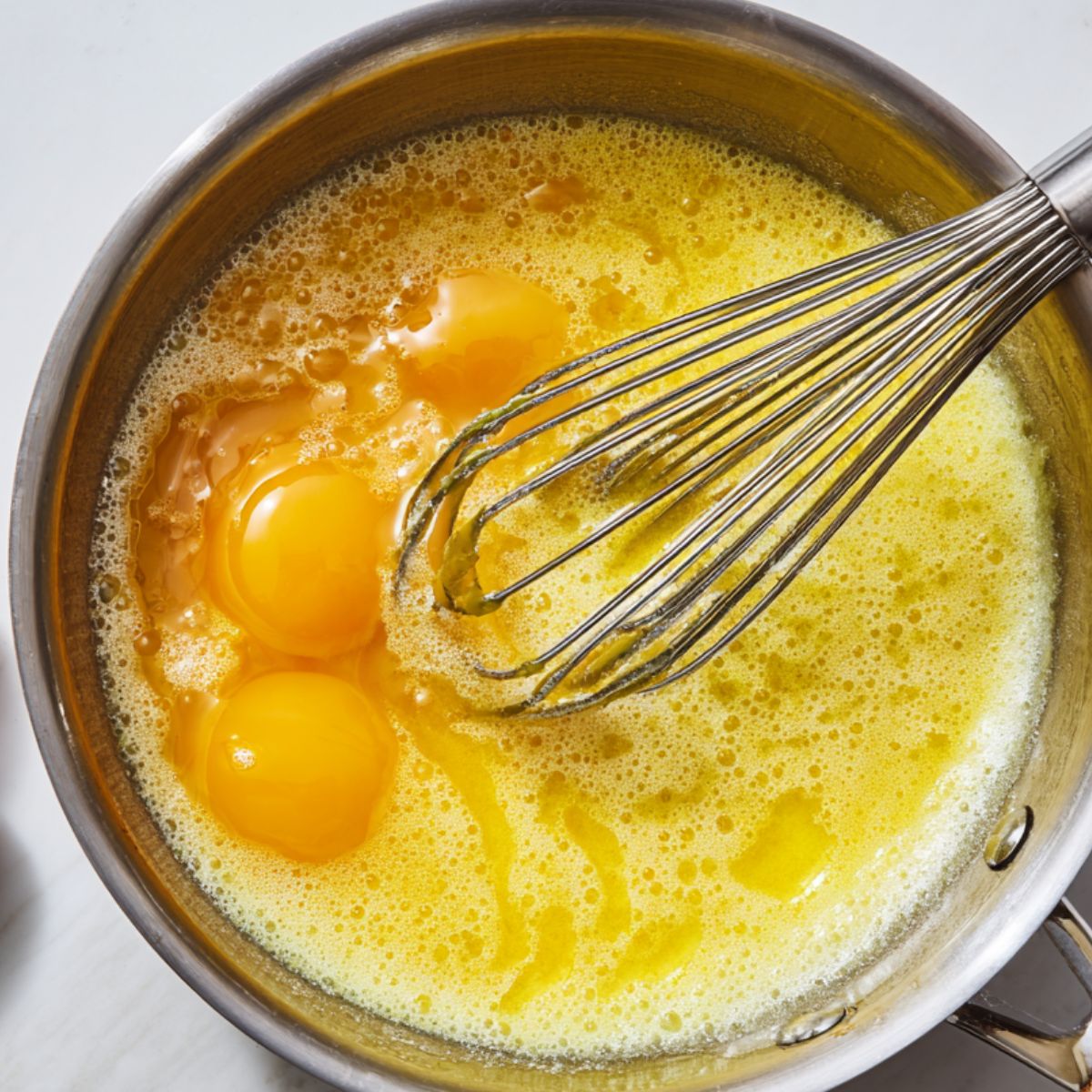 Whisking eggs, sugar, and lemon juice in a saucepan