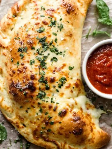 Freshly baked homemade Italian calzone recipe on a white kitchen counter, shot from above by a home cook