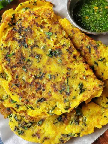Homemade Moong Dal Chilla Recipe, stacked on a white kitchen counter with mint chutney, top-down view