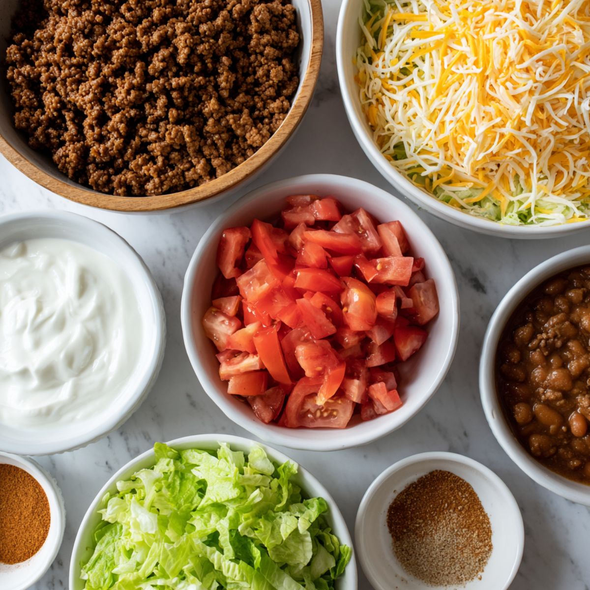 Overhead shot of Crescent Roll Taco Pizza ingredients casually arranged on a white kitchen counter.