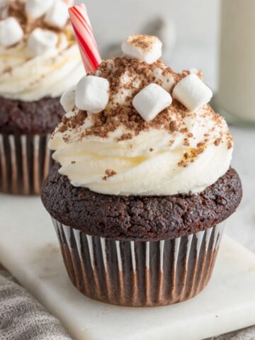 homemade hot chocolate cupcakes with marshmallow frosting on a white kitchen counter