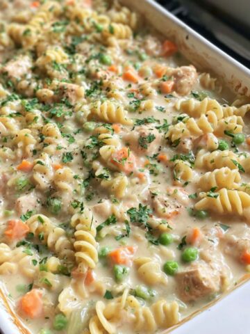 Overhead view of a homemade chicken pot pie pasta recipe , in a baking dish on a white kitchen counter