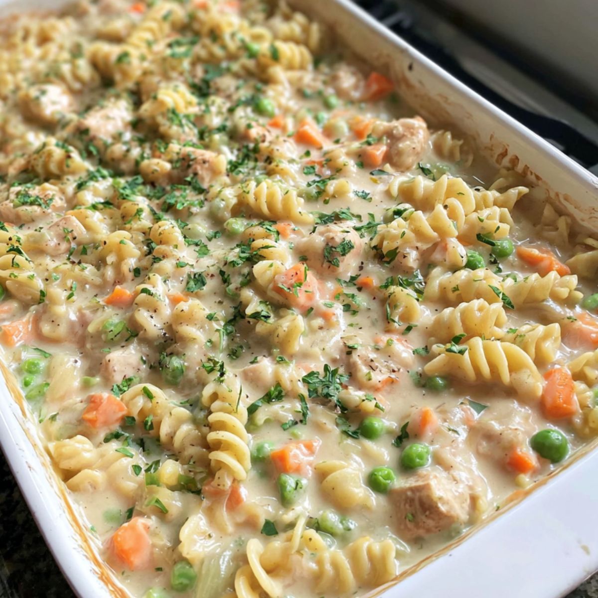 Overhead view of a homemade chicken pot pie pasta recipe , in a baking dish on a white kitchen counter