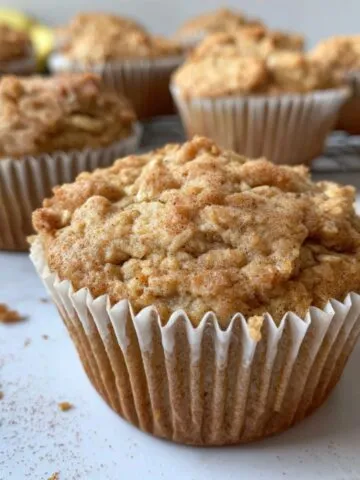 Freshly baked oatmeal cinnamon apple muffins on a white kitchen counter, rustic and homemade.