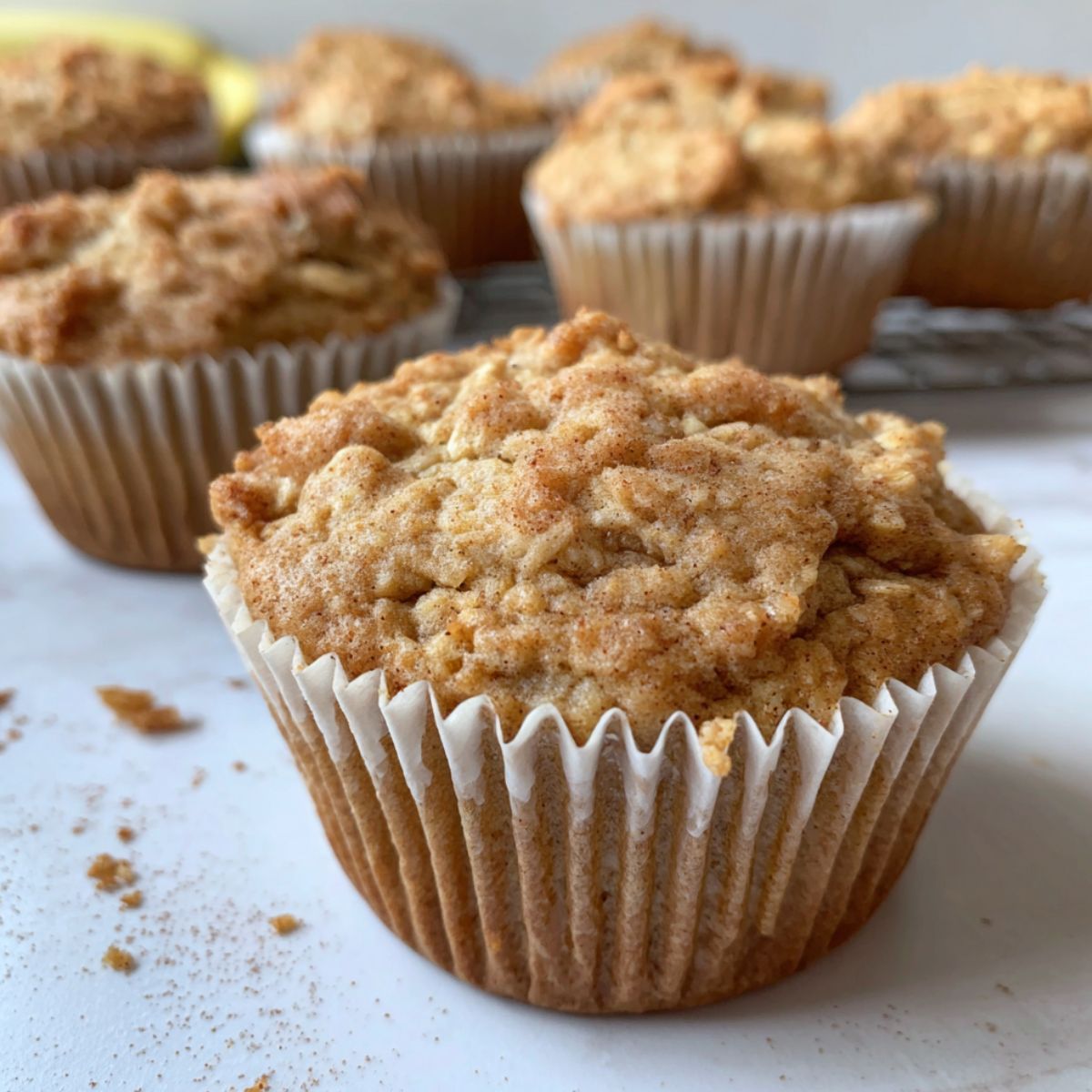 Freshly baked oatmeal cinnamon apple muffins on a white kitchen counter, rustic and homemade.