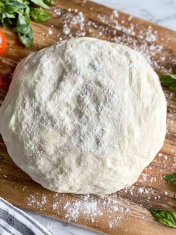 Overhead shot of homemade Neapolitan pizza dough recipe on a floured wooden surface