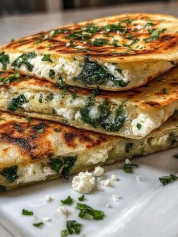 Homemade spinach and feta quesadilla cut into triangles on a white kitchen counter