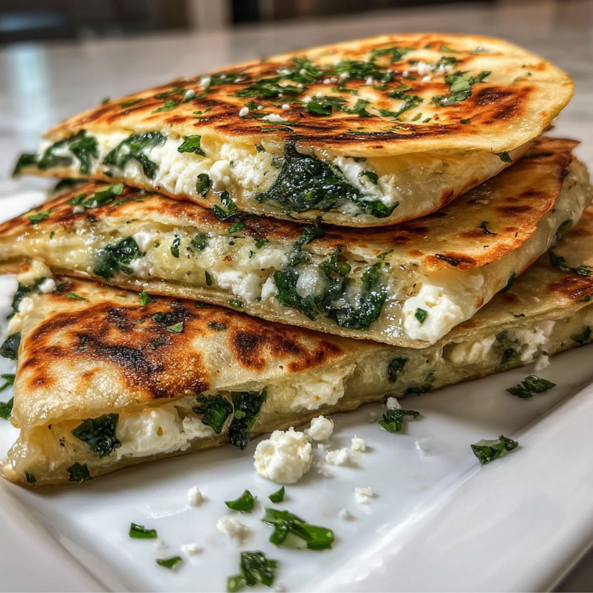 Homemade spinach and feta quesadilla cut into triangles on a white kitchen counter