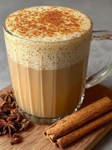 Homemade vanilla cinnamon milk tea with cinnamon stick on a white kitchen counter