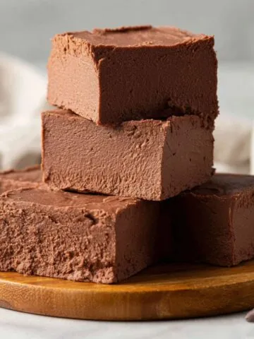 Homemade Marshmallow Fluff Fudge recipe , on parchment paper, casually cut and placed on a wooden board, looking rich and gooey on a white kitchen counter