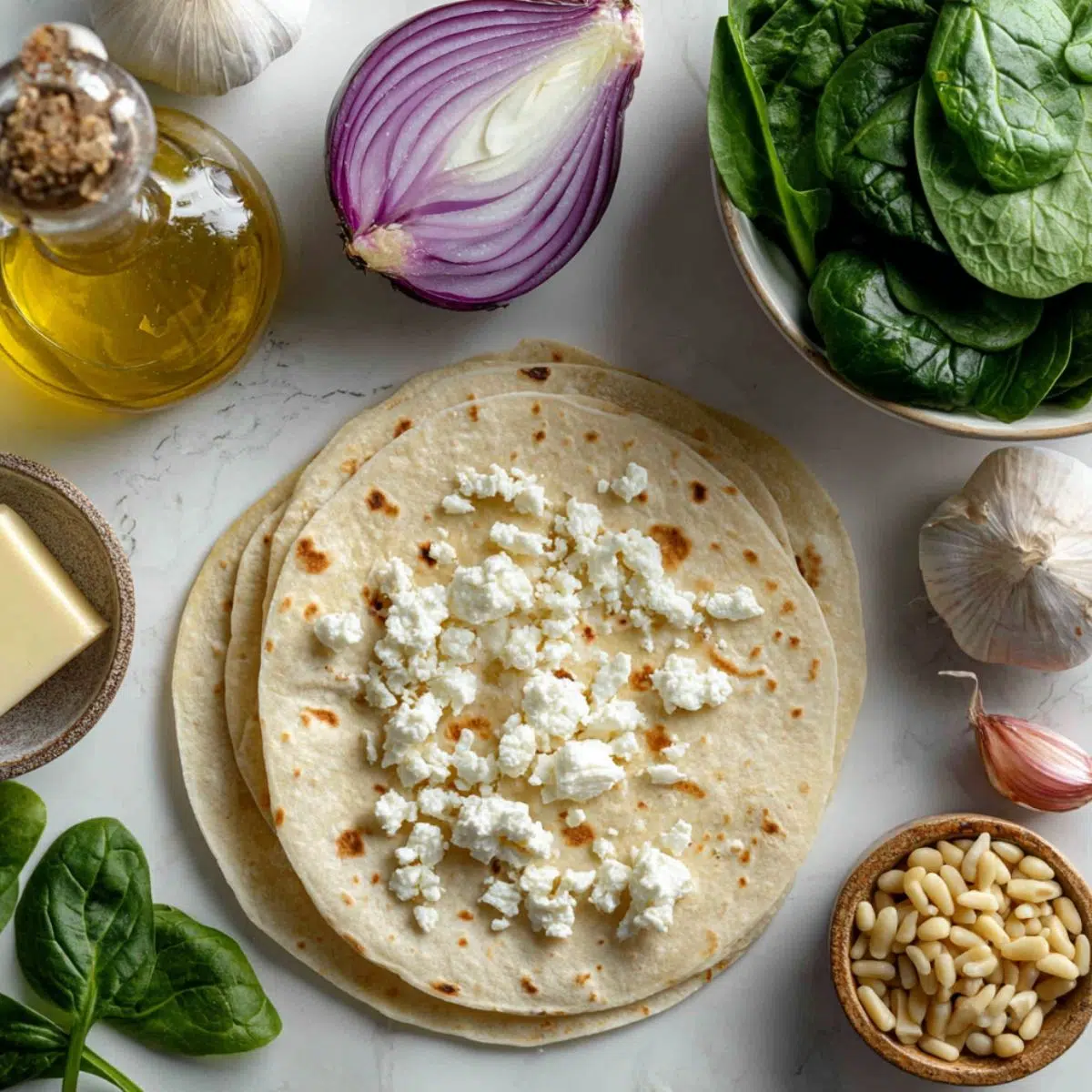 Fresh ingredients for a spinach and feta quesadilla scattered on a white kitchen counter