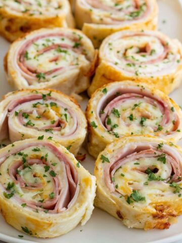 Homemade turkey and cheese pinwheels sandwiches on a plate over a white kitchen counter,