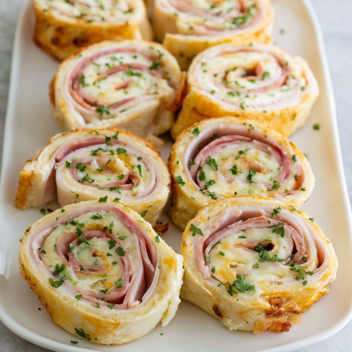 Homemade turkey and cheese pinwheels sandwiches on a plate over a white kitchen counter,