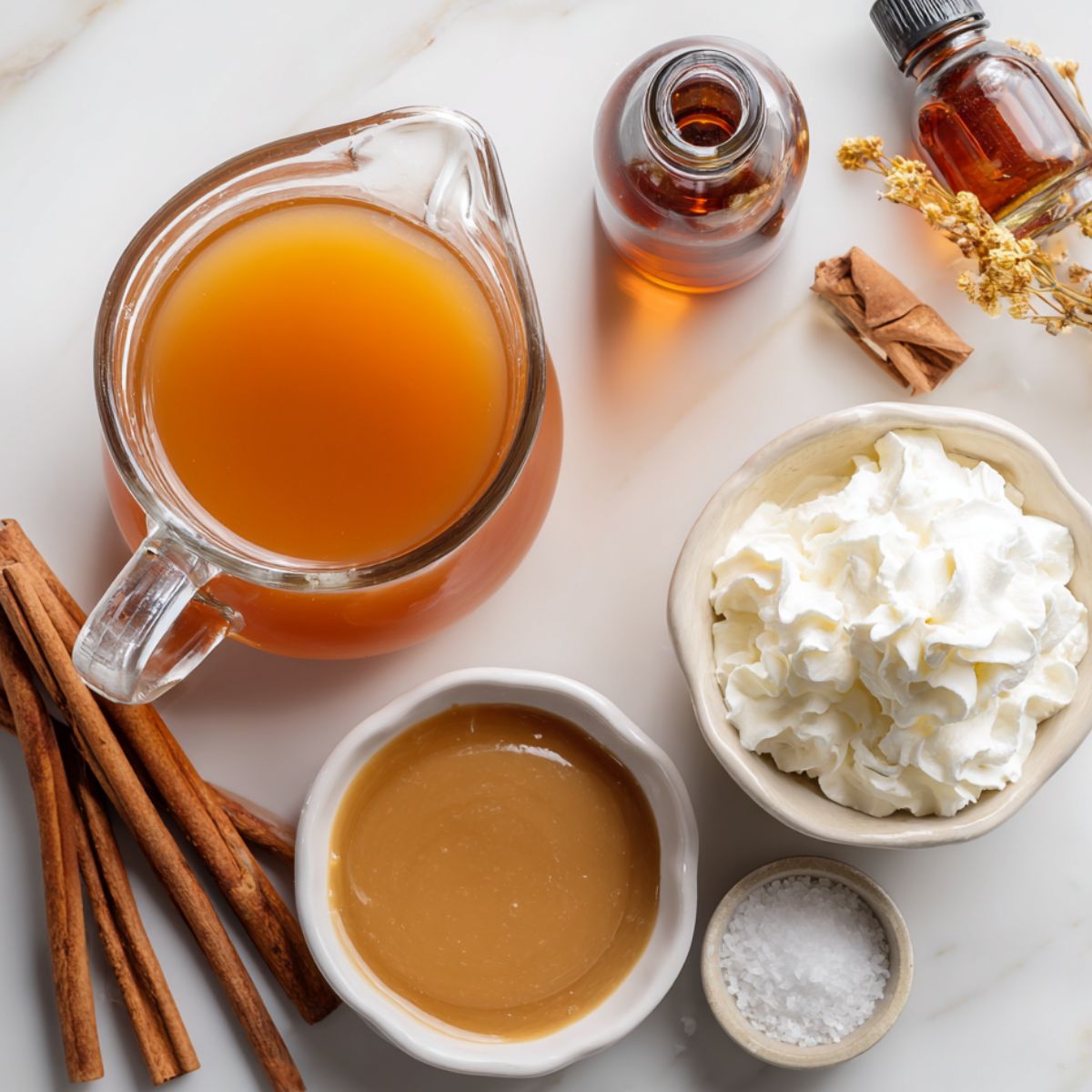 Top-down view of caramel apple cider ingredients casually arranged on a white kitchen counter with natural lighting.