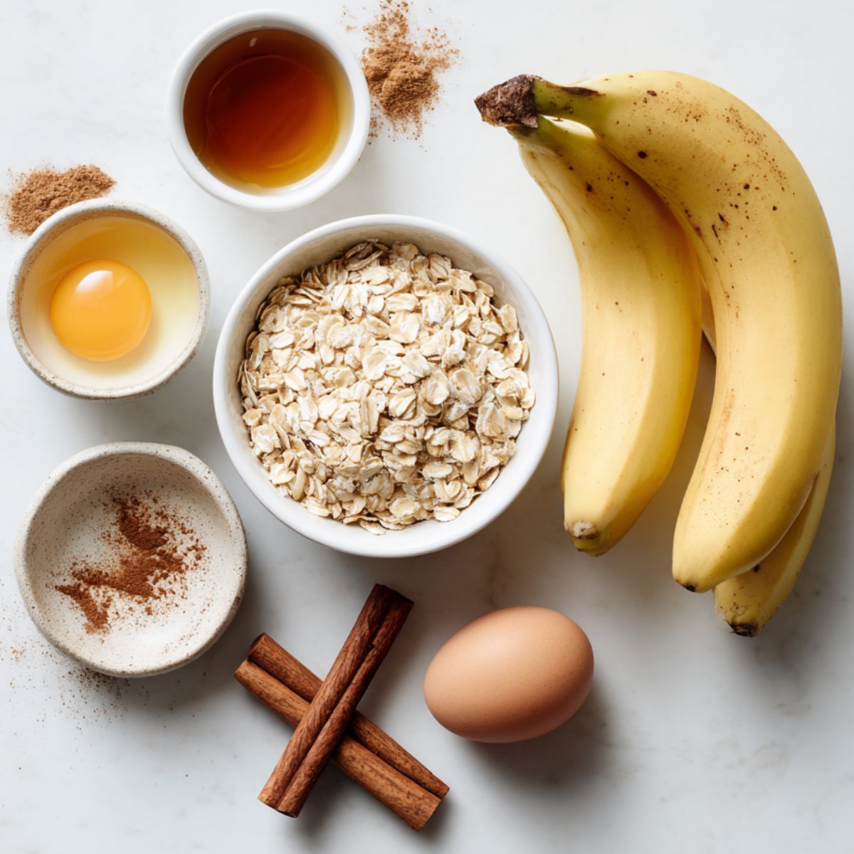 Ingredients for homemade baked oatmeal breakfast bars laid out casually on a white kitchen counter.