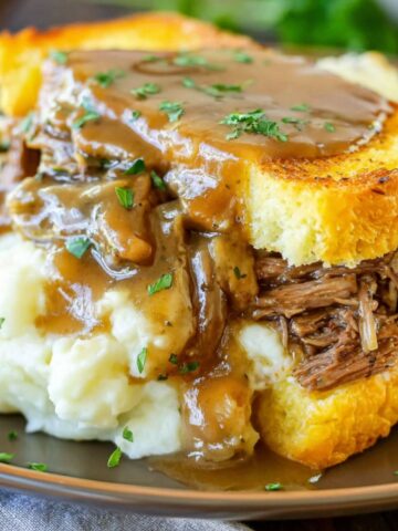 A homemade Beef Manhattan sandwich with mashed potatoes and gravy on a white kitchen counter.