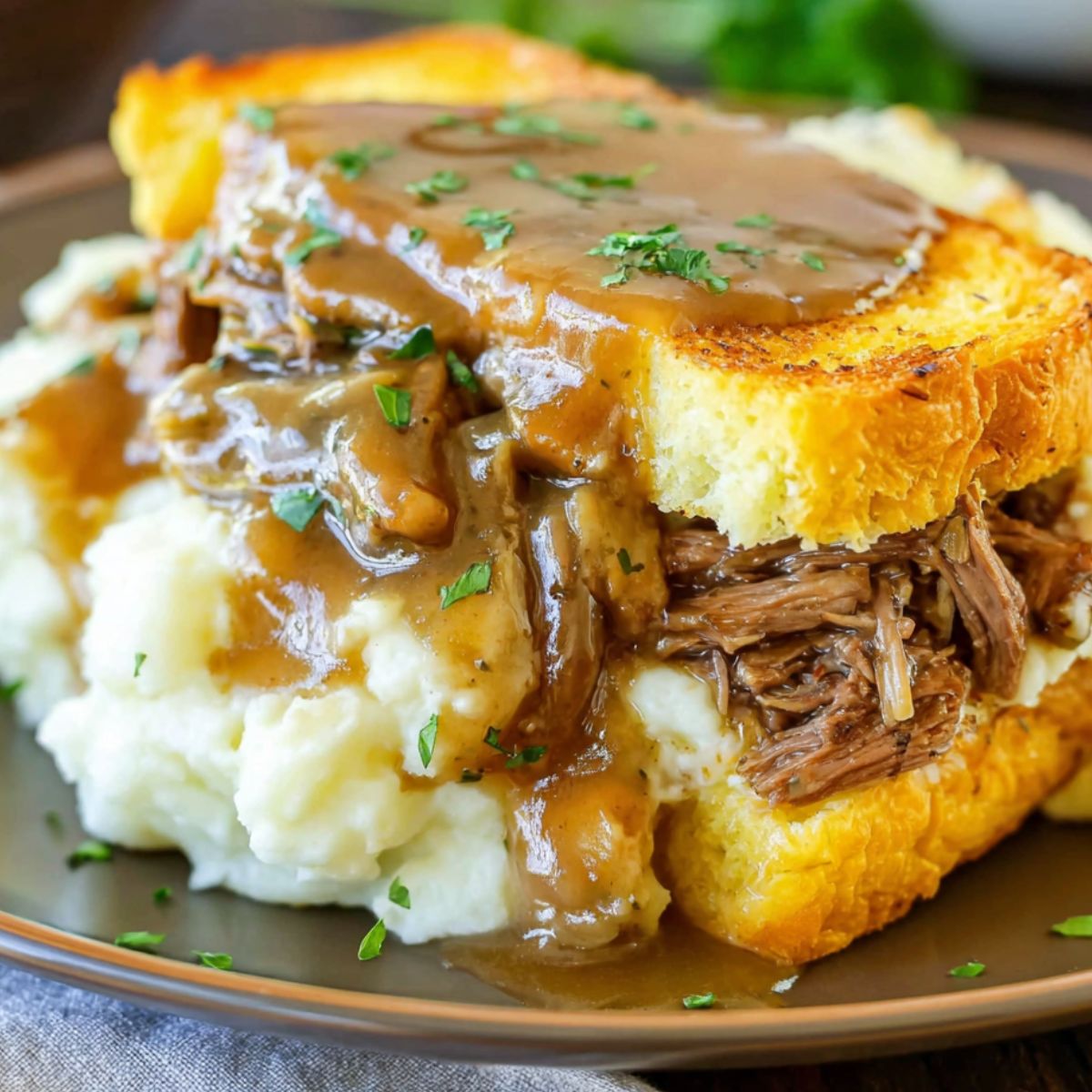 A homemade Beef Manhattan sandwich with mashed potatoes and gravy on a white kitchen counter.