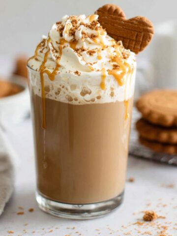 Homemade Biscoff latte on a white kitchen counter with cookie crumbs
