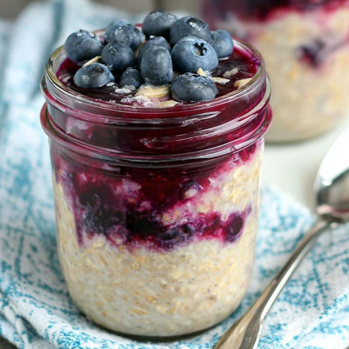Homemade Blueberry Pie Overnight Oats in a mason jar topped with blueberries and granola on a white kitchen counter.