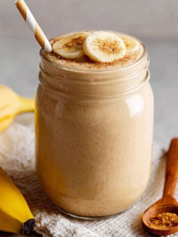 Homemade coffee smoothie with banana in a clear glass jar on a white kitchen counter