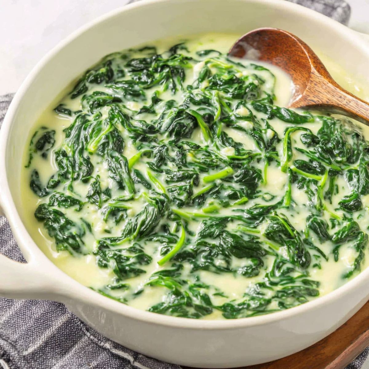 Homemade 3 Ingredient Creamed Spinach served in a simple white bowl on a kitchen counter, shot from above.