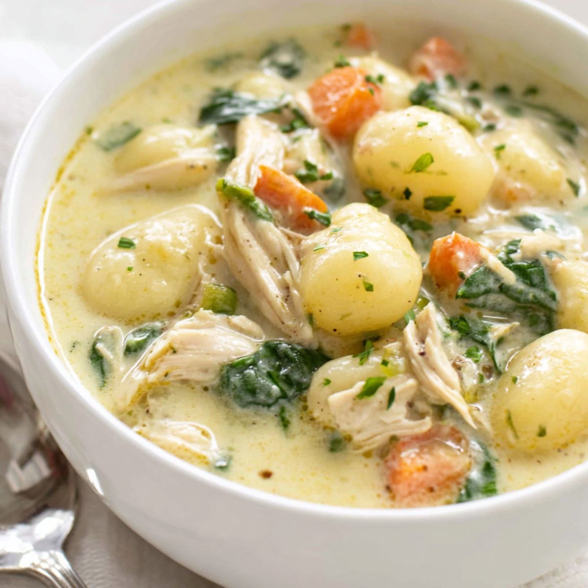 A homemade bowl of creamy gnocchi soup on a white kitchen counter