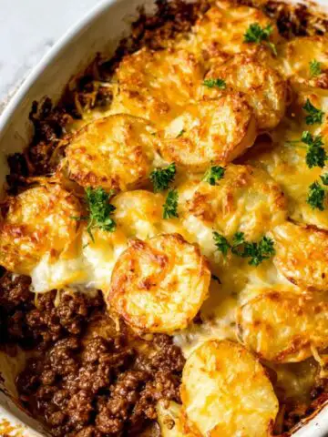 Homemade hobo casserole with ground beef and potatoes in a baking dish on a white kitchen counter, viewed from above.