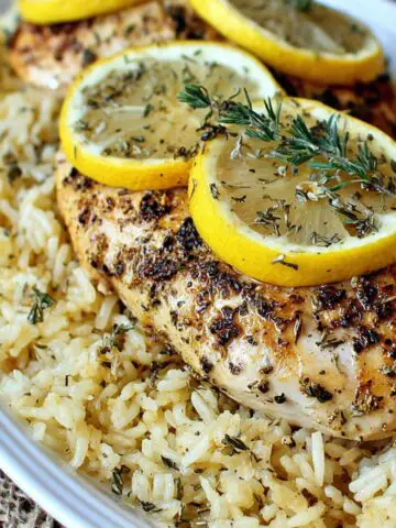 Homemade lemon herb chicken and rice served on a kitchen table.