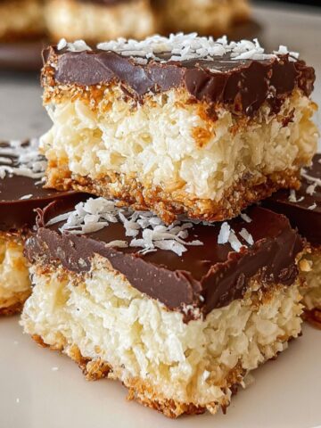 Top-down view of homemade coconut bars with chocolate topping on a white kitchen counter.