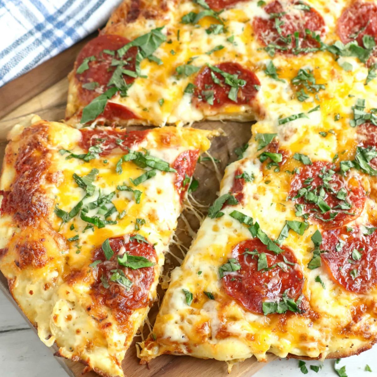 Homemade pizza egg topped with cheese, pepperoni, and basil on a white kitchen counter, top-down view.